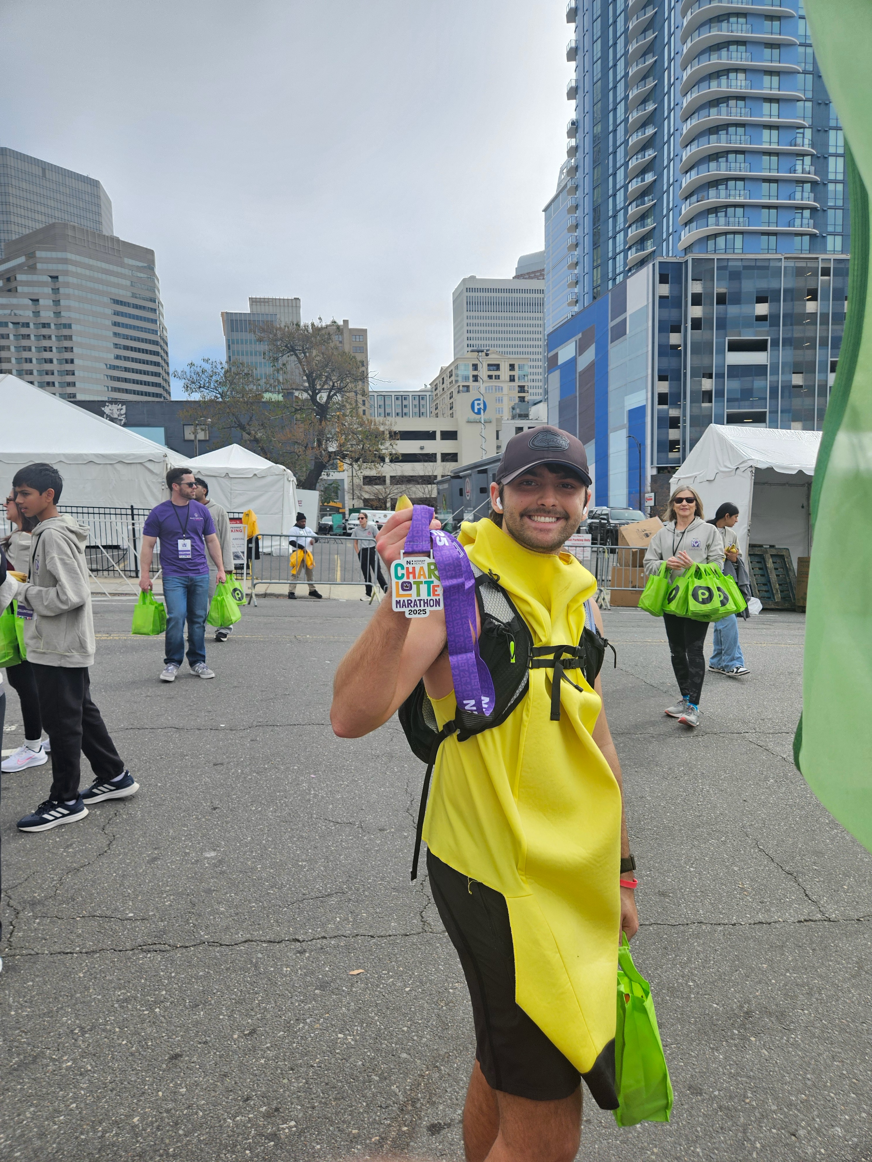 Max holding up his finisher medal in a banana costume at the marathon finish area