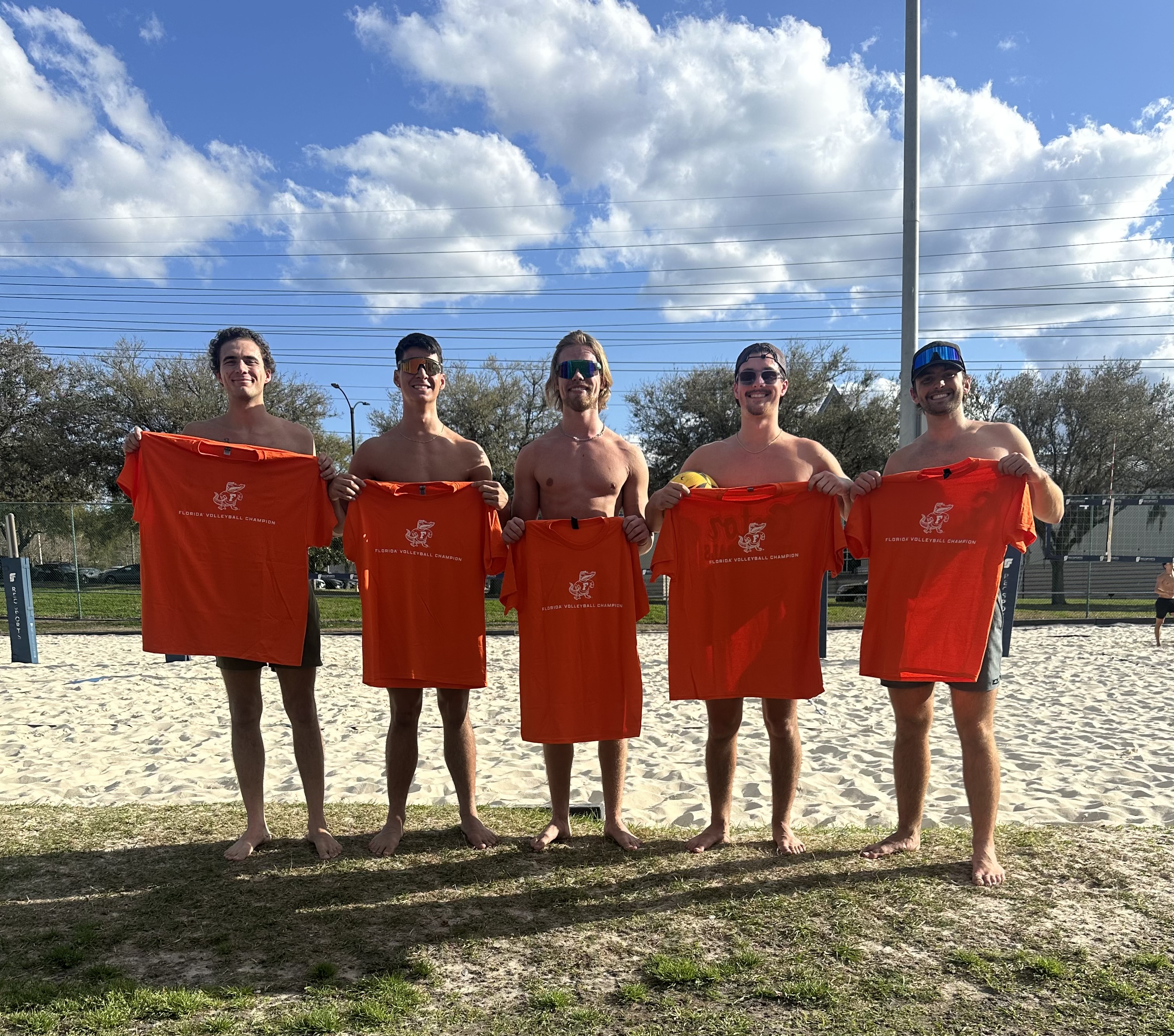 Five teammates with championship shirts on the sand court